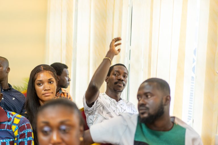 A student raising his hand to ask a question during a training session at the Accra School of Real Estate